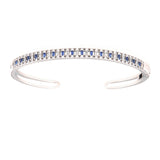 Silver-toned open bangle. Top half has alternating blue rectangular and clear round stones, with clear round stones on each s