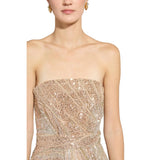 Close-up studio portrait of a model highlighting the intricate, densely sewn diagonal champagne gold sequins and micro-beading on the bodice of the strapless Zuhair Murad gown.