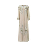 A floor-length beige two-piece kaftan set by SHAIRA featuring a pleated inner dress and a sheer outer robe with heavy ivory floral embroidery and 3D petal details.