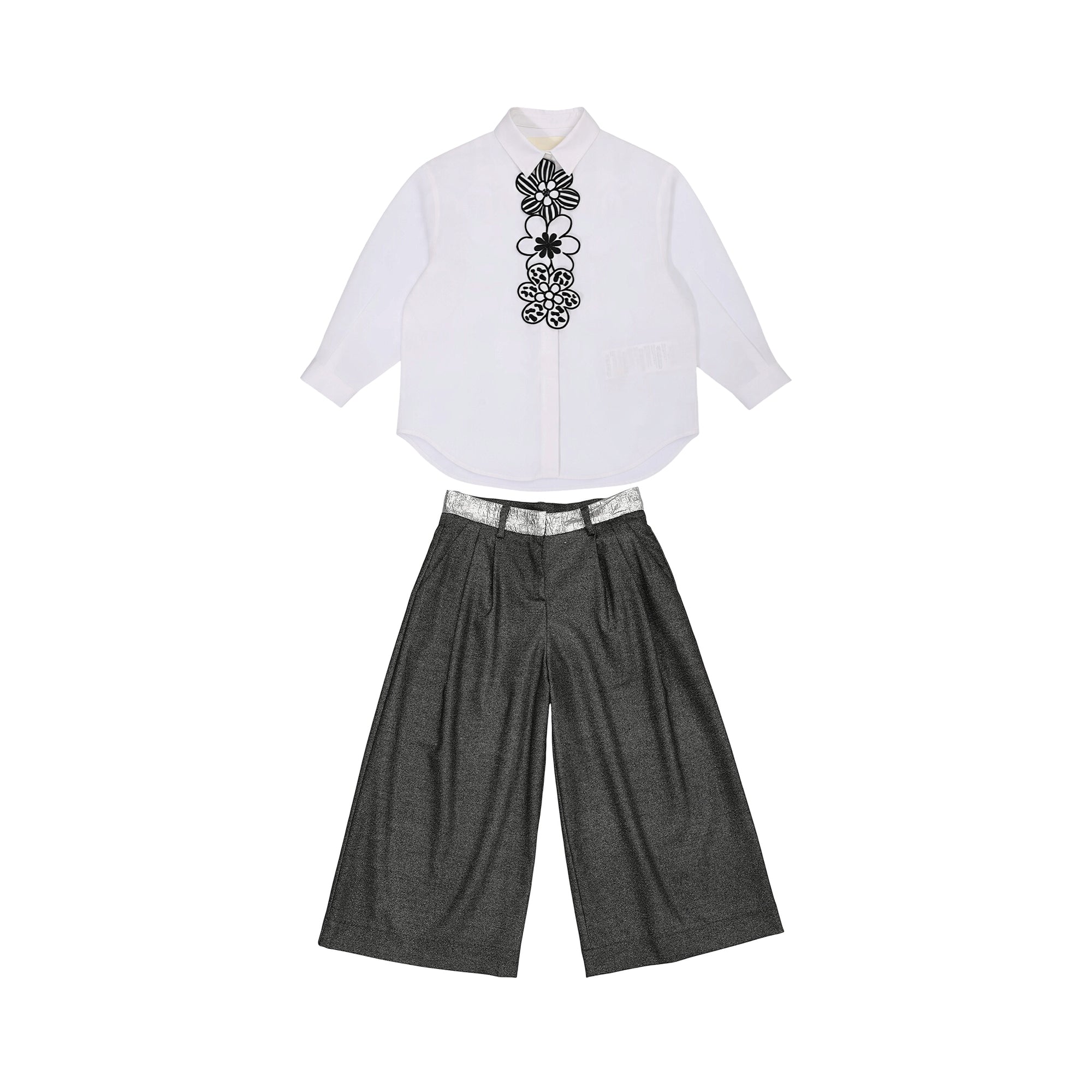 White collared shirt with black and white floral embroidery paired with dark grey wide-leg trousers and a silver-toned waistb