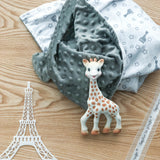 A grey dotted minky blanket with a white side patterned with grey stars and giraffes, and a white Sophie La Girafe toy with o