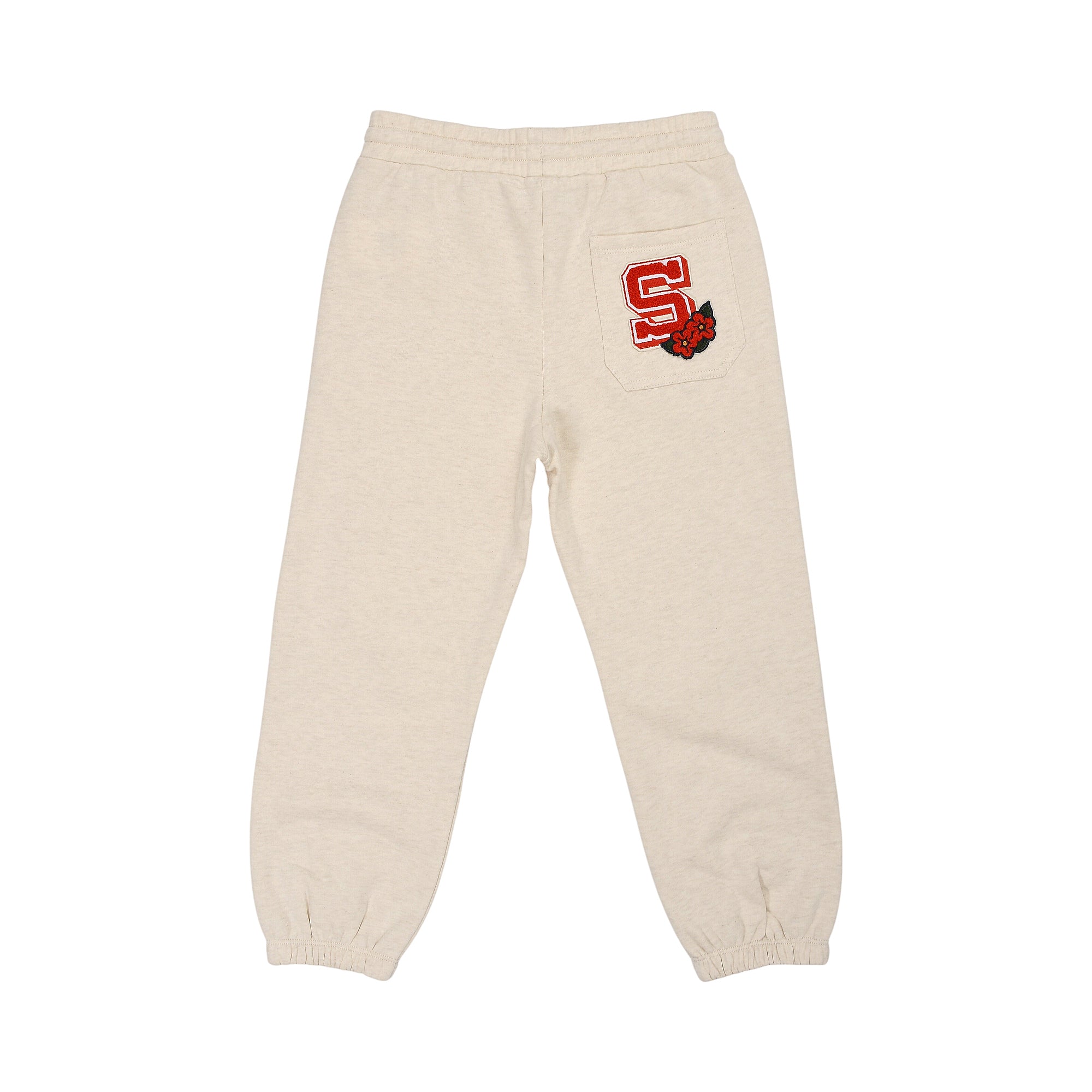 Beige jogging pants with elastic waist and cuffs, featuring a red varsity 'S' patch with red flowers on the back right pocket