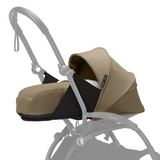 Stokke Kids newborn pack in toffee brown, featuring a structured bassinet and canopy, with black fabric accents and a zipper.