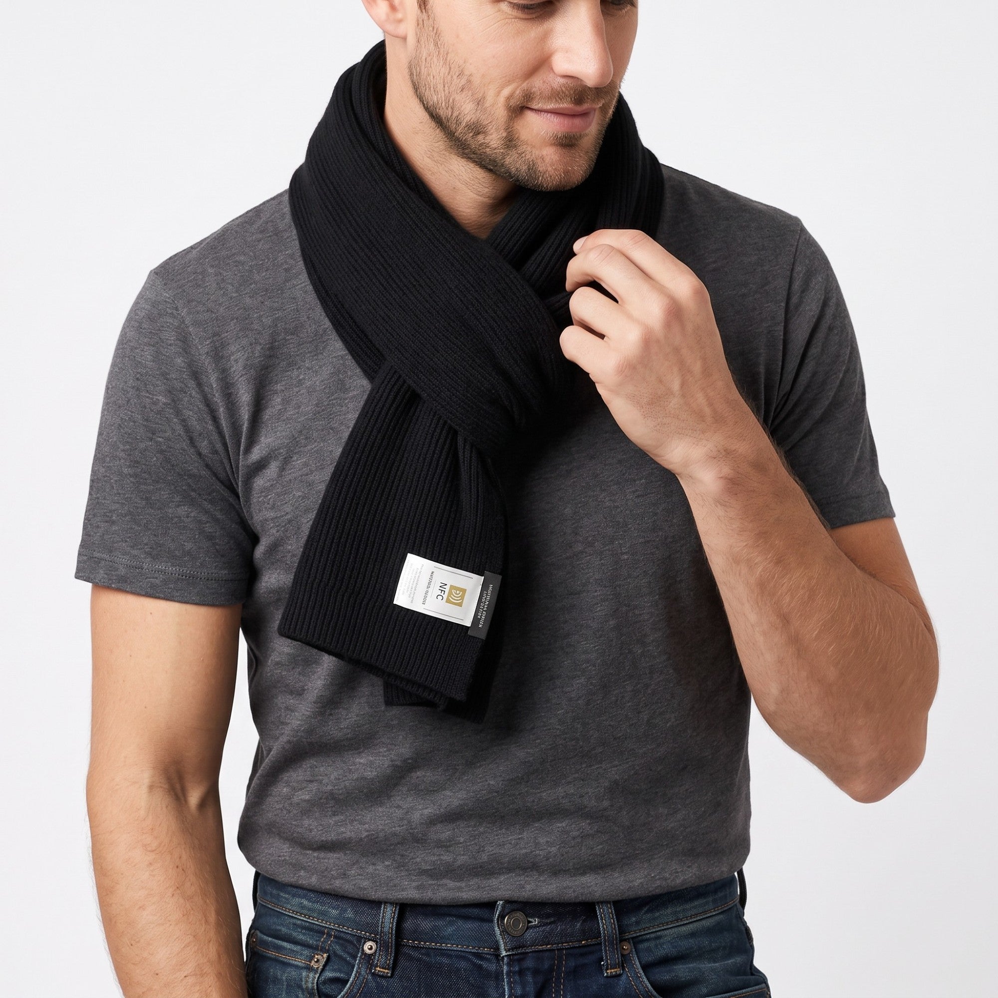 Black ribbed knit scarf with a rectangular shape. A white tag with black text and icons is visible on one end.