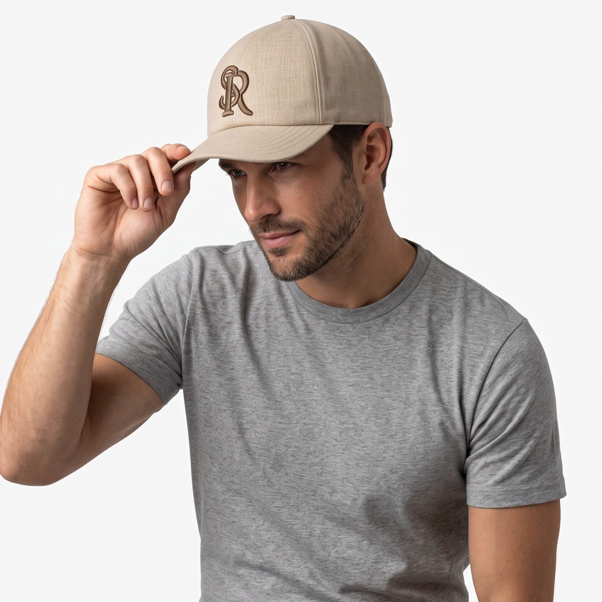 Beige baseball cap with a textured fabric, featuring an embroidered brown stylized 'R' logo on the front.