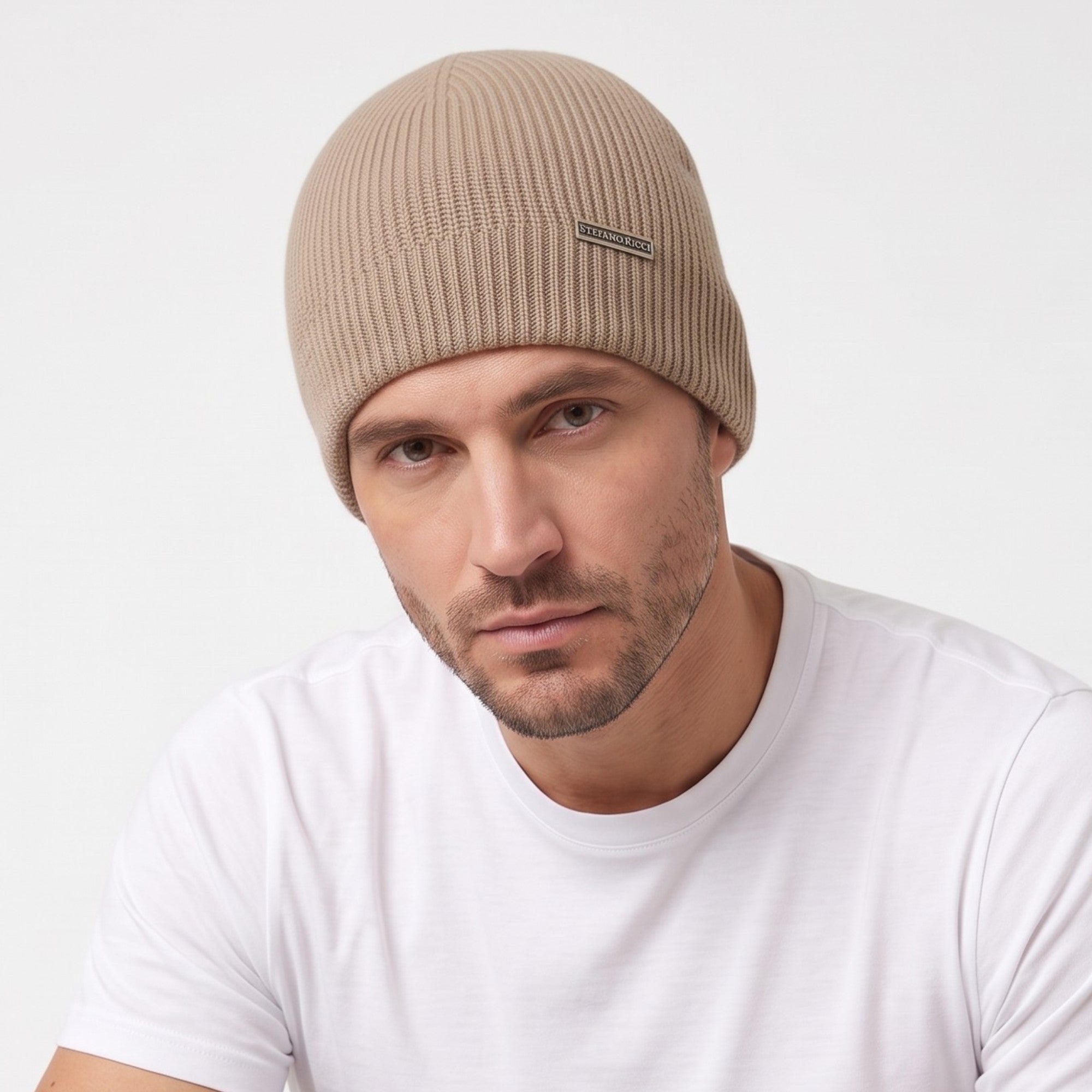 Beige rib-knit beanie hat with a dark-toned rectangular plaque on the front cuff featuring 'STEFANO RICCI' text.