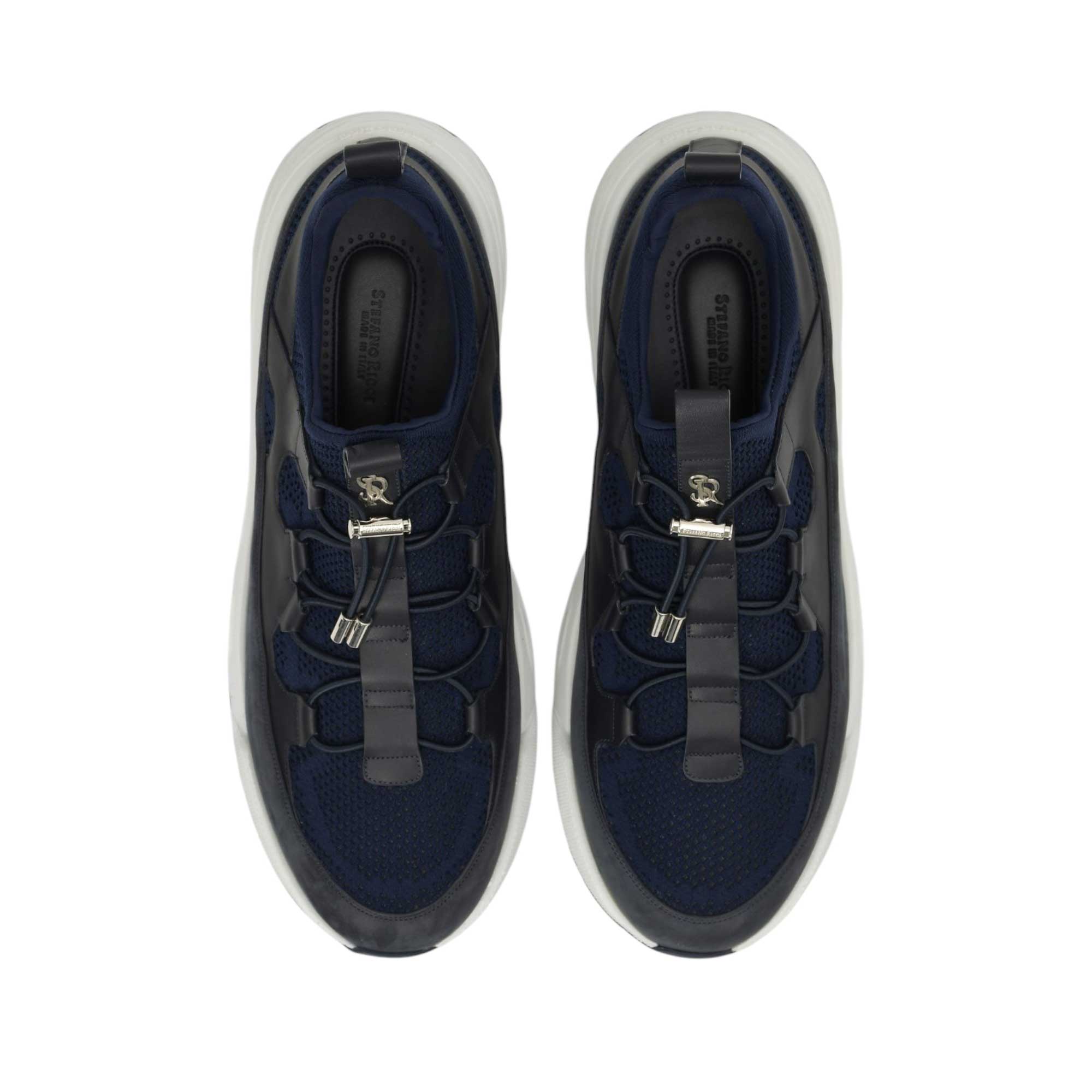 Pair of navy blue mesh and leather sneakers with white chunky soles. Features silver-toned hardware and bungee laces.