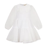 White tiered dress for kids with long sheer sleeves, a round neckline, and two white floral appliqués on the chest.