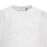 White dress with round neck, puffed sleeves, and two white appliquéd flowers on the front, each with a central cutout.