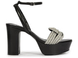 Side profile of the Schutz Keefa platform in black leather, highlighting the contrast between the dark leather and the shimmering crystal-encrusted knot.