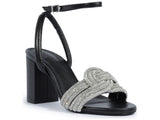 Three-quarter view of Schutz Keefa sandal showing the detailed rhinestone knot embellishment and sturdy black block heel.