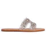 Profile view of a Schutz flat sandal with clear double straps embellished with marquise-shaped crystals on a tan leather sole.