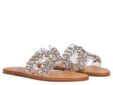 Pair of Schutz clear slide sandals with sparkling crystal floral patterns on transparent straps, shown from an angled side view.