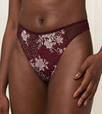 Second Model close-up view of the Triumph Lavish Spotlight burgundy high waist thong, showcasing the intricate lace embroidery and sheer mesh details. Now Available Online