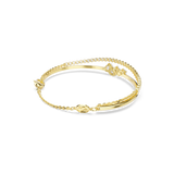 A side perspective studio shot of the Swarovski Mesmera double-strand bracelet draped on a white surface, showcasing the curved structural flow of the gold bar and the fluid layer of the chain beneath it.