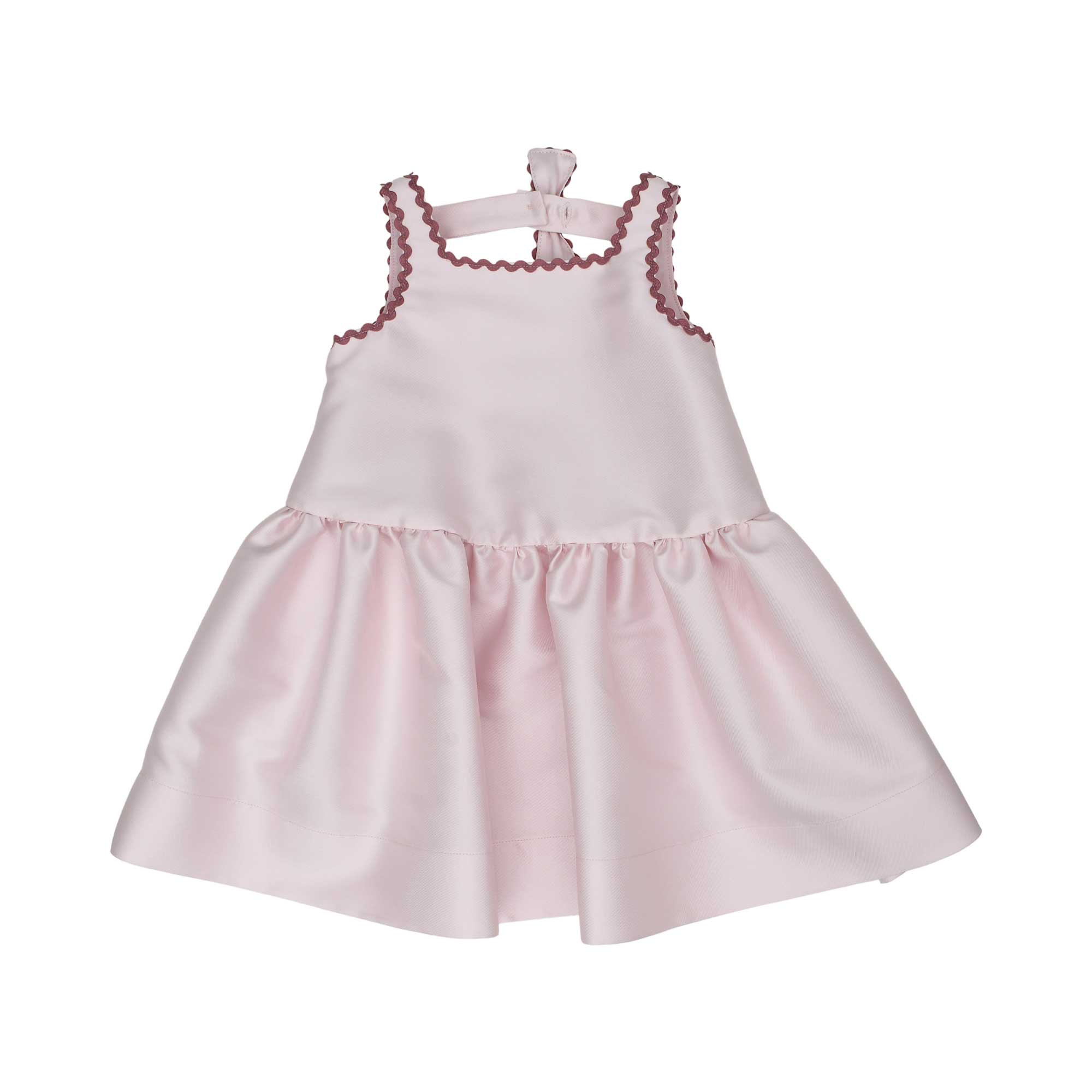 Back view of the Simonetta pink dress showing a rectangular cutout detail, large burgundy-trimmed bow, and gathered skirt.