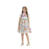 Young girl wearing a white Speranza party dress with a floral embroidered tulle skirt and matching flower headband against a white background.