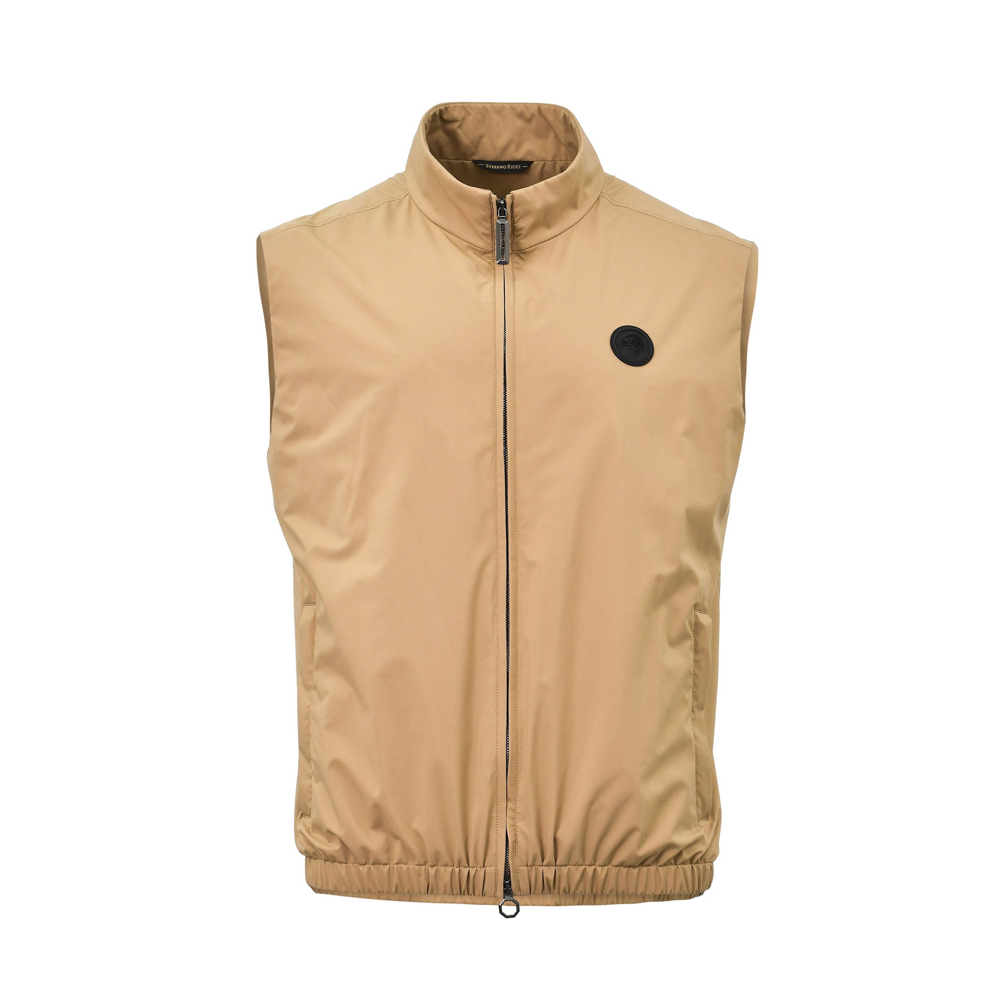 Front view of a men's luxury Stefano Ricci sleeveless zip-up vest in a solid beige color, showcasing a high stand collar, vertical side pockets, an elasticated hemline, and a circular black eagle logo patch on the left chest.