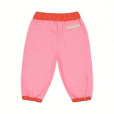 Back view of pink baby trousers featuring an orange elasticated waistband and cuffs, two square rear patch pockets, and a beige Stella McCartney logo badge stitched above the right pocket.