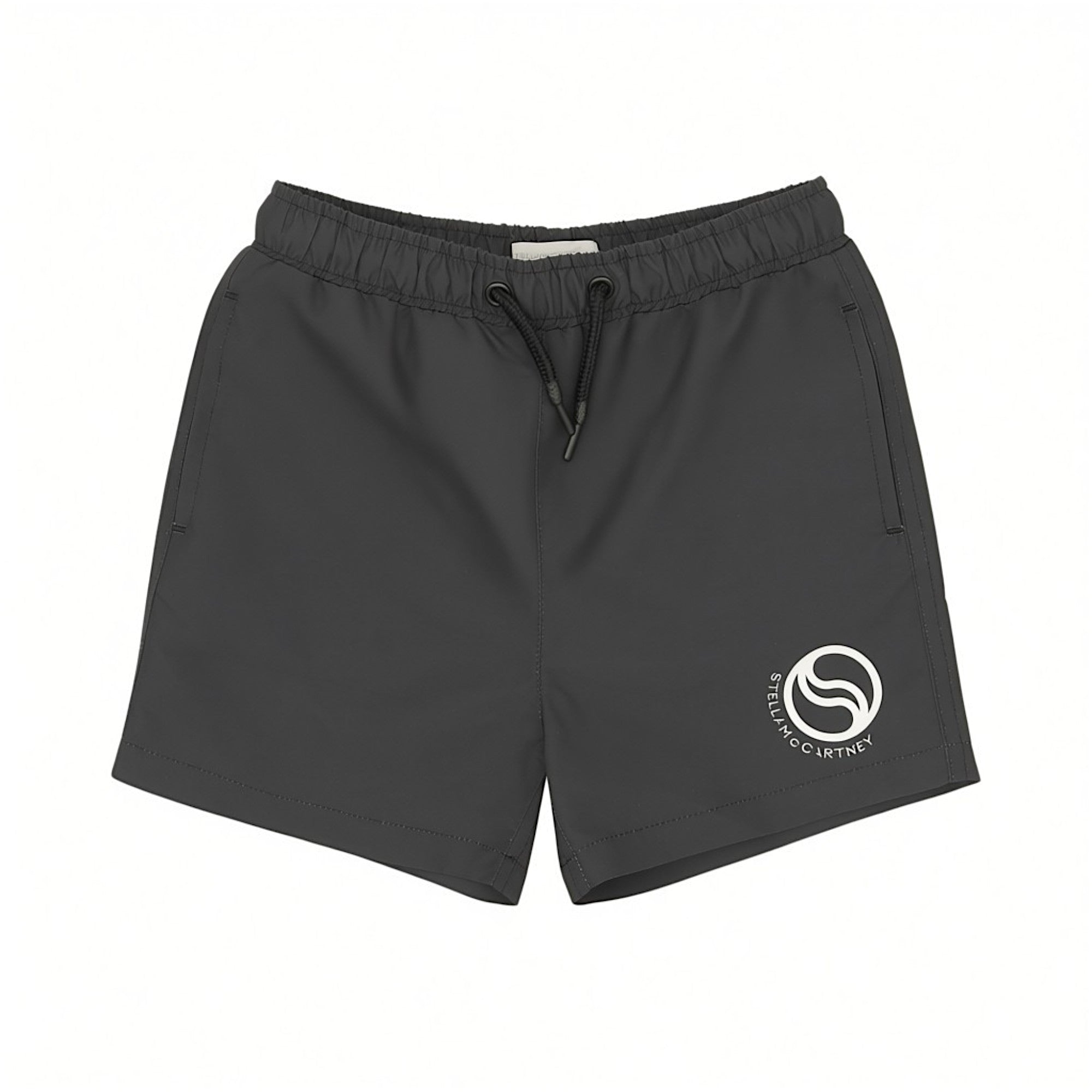 Front view of Stella McCartney Kids swim shorts in dark grey featuring an elasticated drawstring waistband, side pockets, and a white circular logo on the left leg.