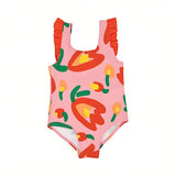Front flat-lay view of a Stella McCartney Kids girls' one-piece swimsuit in pink, decorated with a bold red and yellow abstract floral tulip pattern and matching red ruffled shoulder straps.