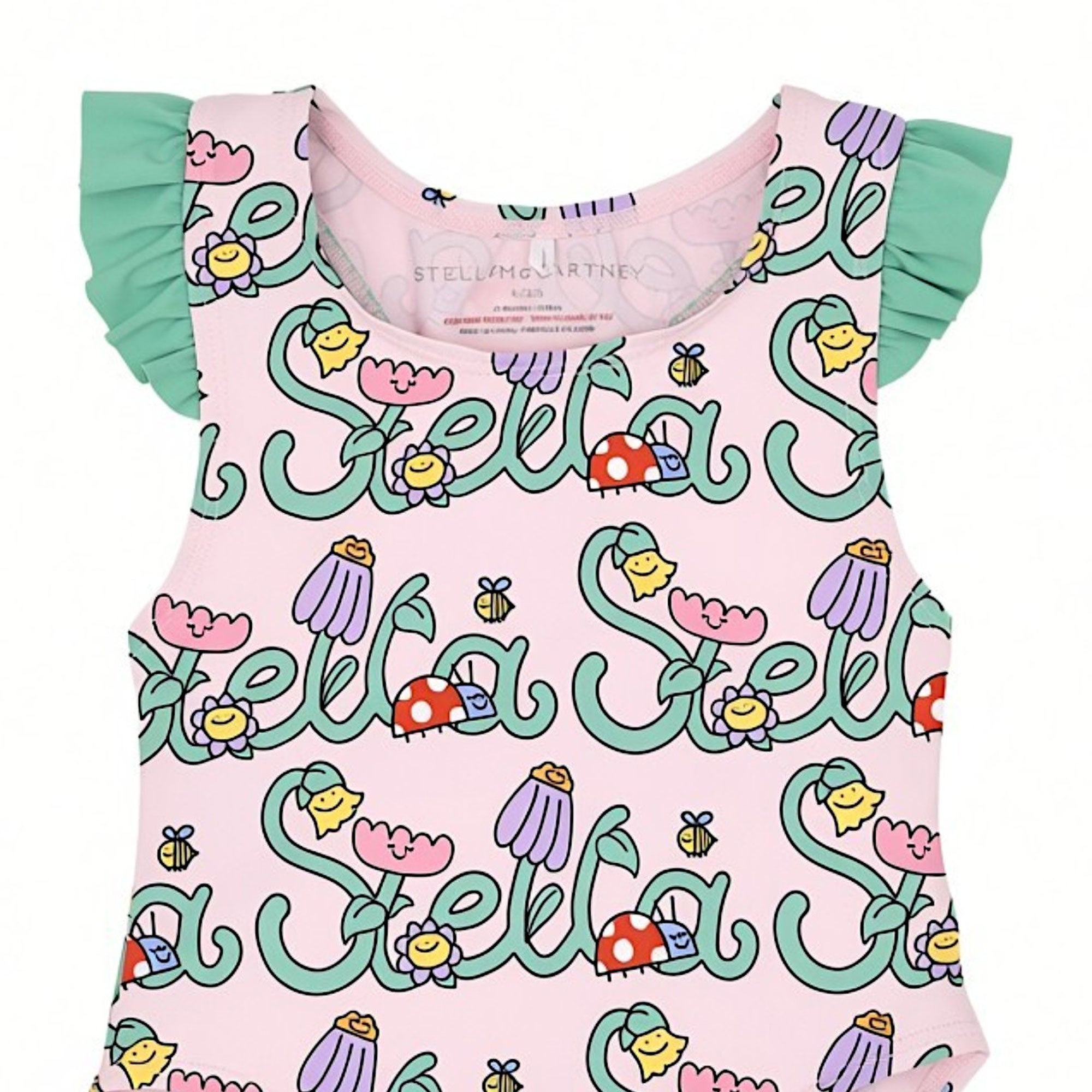Front bodice close-up of a pink kids' swimsuit highlighting the stylized cursive "Stella" text woven with smiling flowers, red ladybugs, and small bumblebees.