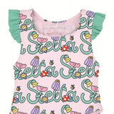 Front bodice close-up of a pink kids' swimsuit highlighting the stylized cursive "Stella" text woven with smiling flowers, red ladybugs, and small bumblebees.