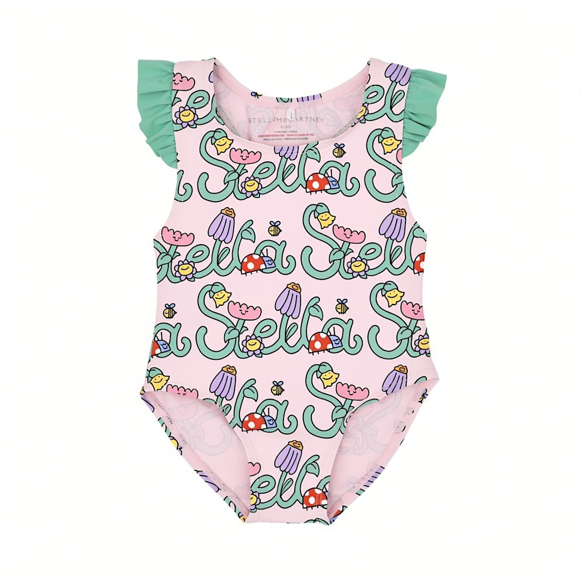Flat lay close-up of a pink Stella McCartney Kids swimsuit showing the inner neck brand stamp, mint green ruffled shoulder straps, and an all-over garden print.