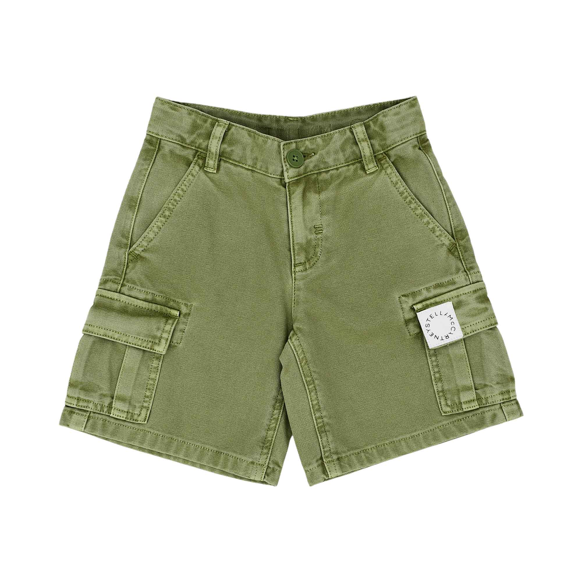 Front view of Stella McCartney Kids khaki green cargo shorts featuring side flap pockets and a white circular logo patch on the left leg.