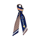 Styled view of the Muni women’s blue printed twilly scarf, with belt buckle motif and brown polka dot detailing. Available for Online Purchase