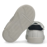 White low-cut sneakers with navy blue heel tabs. One light grey textured sole displays 'TOMMY HILFIGER' and '20'.