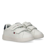Pair of white Tommy Hilfiger Kids low-cut sneakers with two Velcro straps, blue heel tab, and red and blue flag logo.
