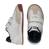 Beige suede and white low-cut sneakers with two white velcro straps, navy blue collar, and brown rubber outsoles.