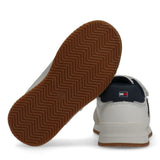 Low-cut white/beige velcro sneaker with dark blue heel tab and logo, white midsole, and brown rubber outsole with zig-zag gri