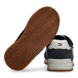 Navy blue low-cut sneaker with white accents, a white heel counter with flag logo, white midsole, and brown zigzag rubber out