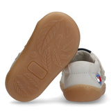 White mid-cut velcro sneaker with a gum-colored sole featuring leaf patterns and 'BAREFOOT' text. A circular logo is on the o