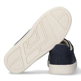 Navy blue low-cut sneaker with cream sole, seen from back. Other sneaker's off-white sole shows geometric patterns.