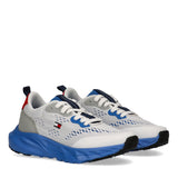 Pair of white Tommy Hilfiger Kids low-cut trainers with blue sculpted soles, grey overlays, and red heel pull tabs.