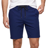 Mid-section studio shot of a male model wearing the deep blue Tombolini drawstring shorts, styled casually with a tucked-in white crewneck t-shirt.