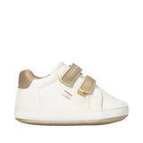 Off-white low-cut sneaker with two nude-toned velcro straps, a metallic gold heel tab, and a metallic gold sole trim.