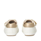Pair of off-white low-cut sneakers with gold-toned heel tabs, velcro straps, and sole trim, seen from the back.