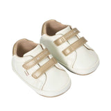 Pair of off-white low-cut sneakers with two gold-toned velcro straps, gold-toned heel collars, and 'TOMMY HILFIGER' branding.