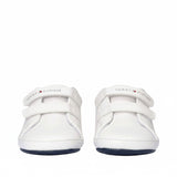 Pair of white low-cut sneakers with two white velcro straps, white stitching, and navy blue soles. Tommy Hilfiger logo on top