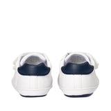 Pair of white low-cut sneakers with navy blue heel counters and soles, featuring white velcro straps.
