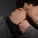 Black leather twincord bracelet with a silver-toned "POLICE" plaque and a textured silver-toned bead.