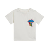 Ivory short-sleeved t-shirt with a blue glitter cloud and fringed rainbow appliqué on the chest.