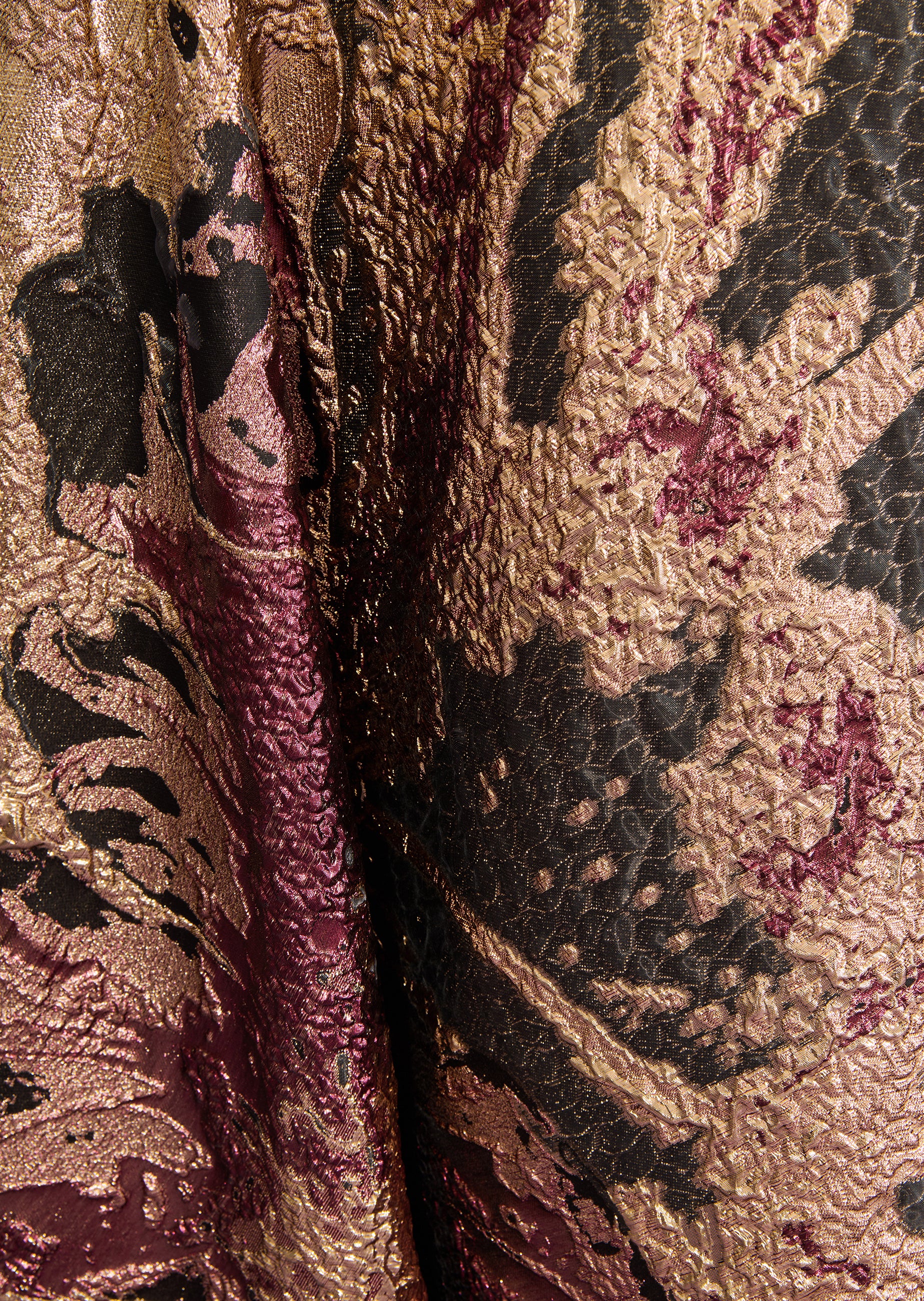 Crinkled long skirt with an abstract pattern in bronze-toned, black, and burgundy fabric.