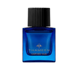 A 100ml square vibrant blue glass bottle of Thameen Carved Oud featuring gold lettering and topped with a textured black cylindrical cap.