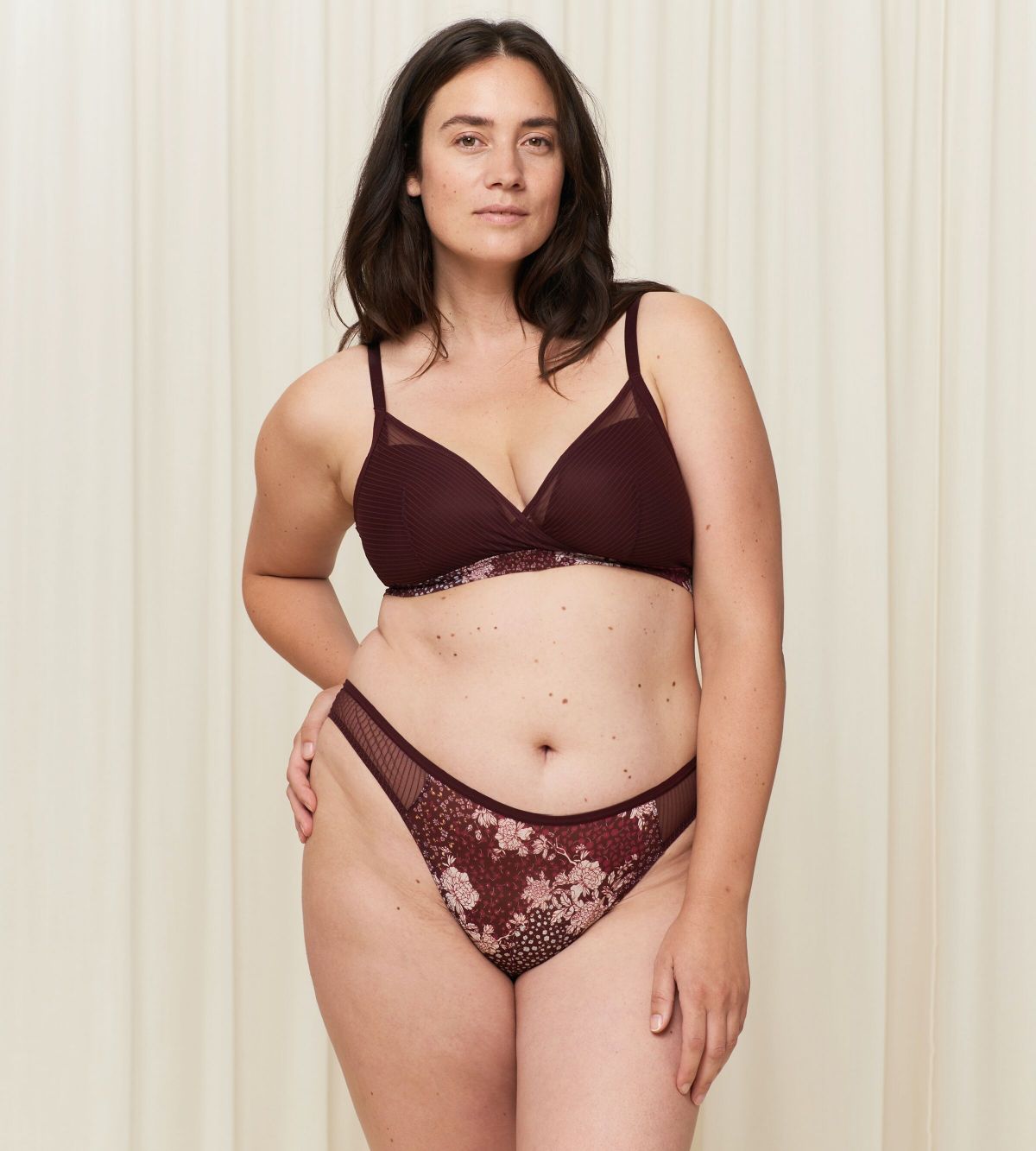 Third Model full front view of the Triumph Lavish Spotlight burgundy high waist thong, showcasing the intricate lace embroidery and sheer mesh details. Now Available Online