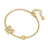 A three-quarter perspective studio view of the Saint Honoré Orsay gold-plated chain bracelet resting on a white surface, showcasing the two-tone butterfly station, central SH logo link, and lobster clasp extender.